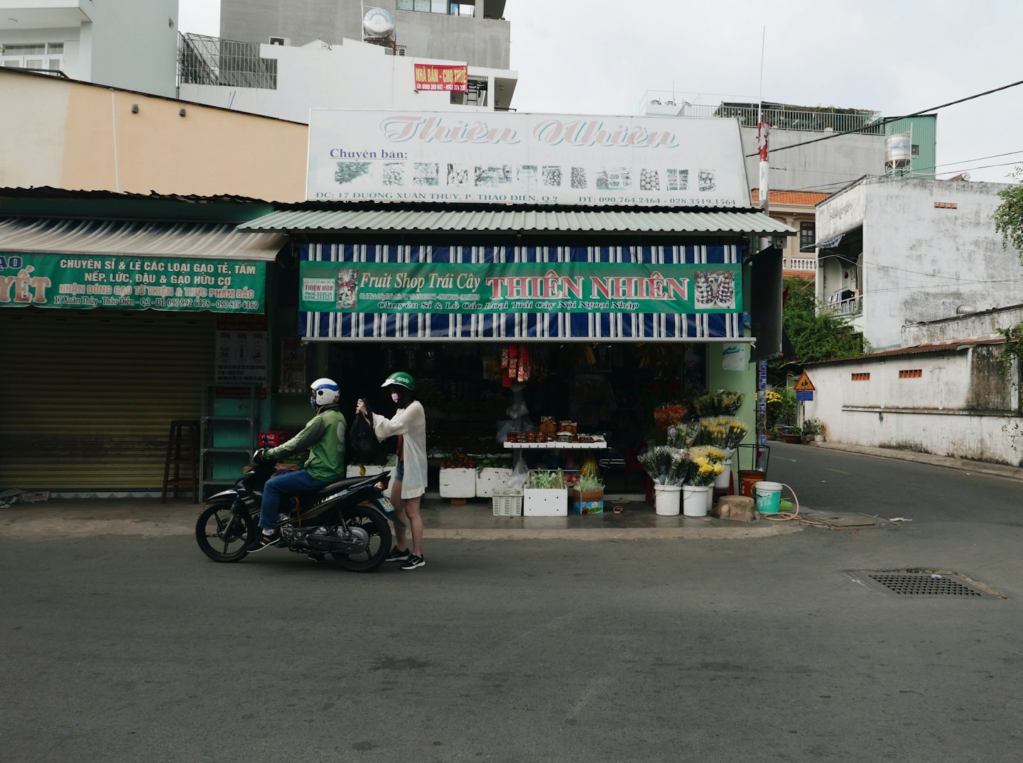 Delivery driver on a motorbike receives a bag outside a grocery store.